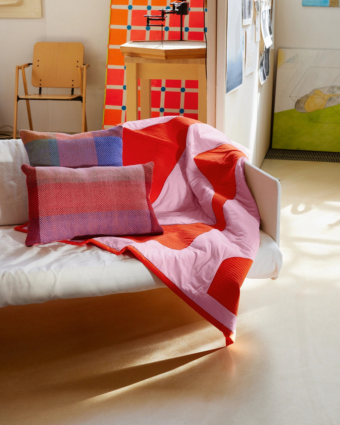 Colorful bedspread and pillows on a bed in a room with a colorful wall and chair.
